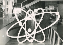 Men preparing the stage for the conference. 
One of them is holding a giant mock-up of an atom. 
(IAEA Archives/Credit: Photo Ellinger)