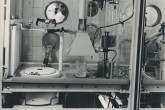 Installation presented by the French Government.  The picture shows the interior of the airtight cell, the lead-shielding and, through the radiation proof window, Professor Alexandre Sanielevici, of the Division of Research and Laboratories, opening a container with the help of a manipulator (left foreground).  February 1963.  Please credit IAEA  